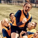 female soccer team celebrating a win and lifting up one of the players on the stadium field after the game