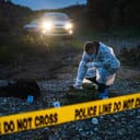 Forensic police investigator collecting evidence at the crime scene in nature at night