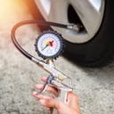 Handheld tyre pressure gauge being used by a person
