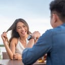 young woman twirling her hair and listening carefully to her date at an outdoor cafe