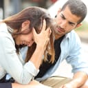 man comforting a sad girl at a train station