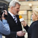 A female journalist with a microphone interviewing a businessman.