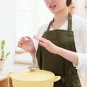 A woman in pain looking at her hand while cooking