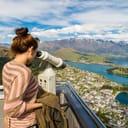 Woman looking over a city through a telescope