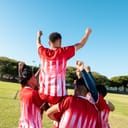 A soccer player being carried on the shoulders of his teammates