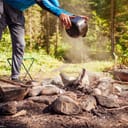 man extinguishing a campfire with water
