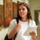 A young woman standing with a notebook in a museum