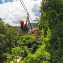 A woman going down a zip-line over a forrest