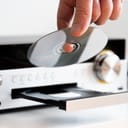 A person placing a CD in a home stereo system