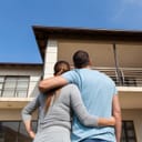 Couple holding each other looking at a property