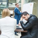 Man hiding his face in discomfort as he takes part in a business presention