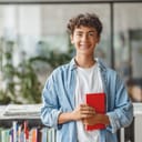 Portrait of smiling curly-haired teenage boy holding a book and looking at the camera. 