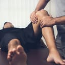 a male therapist performing knee massage on an athlete patient in a sports physical therapy session