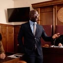 A confident lawyer in professional attire addressing the prosecution during a courtroom trial.