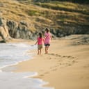 Two girls walking on the beach near the sea leaving footprints