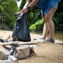 A man collecting trash after having a picnic in the forrest