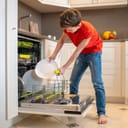 Boy putting dishes into an open dish-washing machine