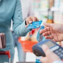 woman at the checkout giving a credit card to the shop clerk to pay for her purchases