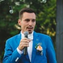 Man in blue suit holding microphone doing a wedding speech
