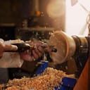 A wooden bowl being turned by a man on a woodturning lathe