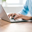 A close-up shot of hands typing on a laptop