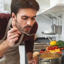 Young man cooking romantic dinner at home taste soup