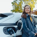 Young woman waiting while her electric car charging in home charging station, sustainable and economic transportation concept.