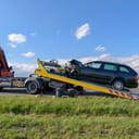 The wrecked vehicle is hoisted onto a tow truck after an accident.