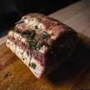 A juicy pork roast with herbs on a cutting board
