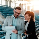 A man and woman looking at notes in an arena