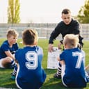 A coach talking with his young players on the soccer field