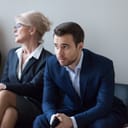 A tense and nervous young man waiting for his job interview, while sitting among other candidates.