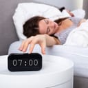 Woman turns off alarm clock that reads 07:00