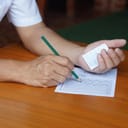 close-up of a student cheating while taking an exam, with answers in his other hand