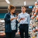 A store manager teaching a new, young employee the ropes