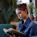 young woman reading a book on a couch, relaxed in a cozy living room