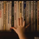 a hand reaching for a book on a shelf, books by Agatha Christie