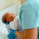 Doctor pediatrician examining new born baby boy in clinic. Nurse dressing infant baby boy. Medical checkup. Health care concept.