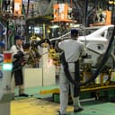 Two employees working on assembling a car in a factory