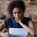 Dissatisfied woman looking at a piece of paper at table
