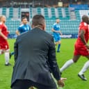 Soccer coach watching a match with disappointment as teams play during a championship in a stadium