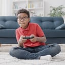 Boy holding a console controller in front of a sofa