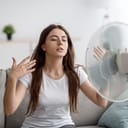 A young woman cooling herself off with a fan