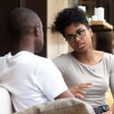 Two young people sitting on a sofa at an office talking