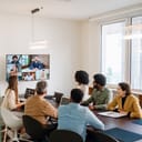 In-office team members having a meeting with remote colleagues on a large screen, modern office setup
