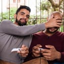 One man placing his hand over another's while playing video games