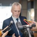 Serious man. Grey-haired bearded man looking concentrated at the press conference