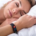 woman sleeping in bed with a wearable health monitor on her wrist