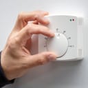 Close-up photo of a hand adjusting a dial on a thermostat