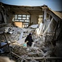 Woman walks through rubble following an earthquake.